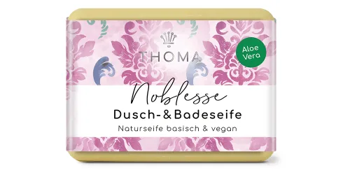 rechteckige, cremefarbene Seife mit pink-lilafarbener Verpackung und Aufschrift Noblesse, feine Sheabutterseife vegan von der Naturseifen Manufaktur Uckermark.