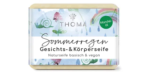 rechteckige, cremefarbene Seife mit blauer Verpackung und Aufschrift Sommerregen, Gesichts und Körperseife mit Mandelöl und Kokosmilch von der Naturseifen Manufaktur Uckermark.