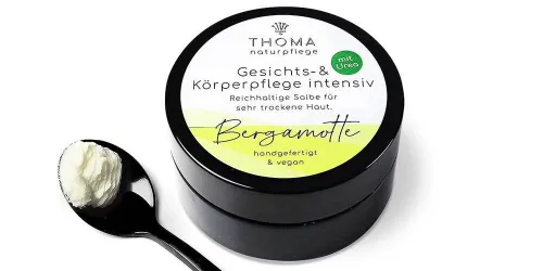 Runde, schwarze Dose mit weiß-gelber Aufschrift Gesichts und Körperpflege intensiv Bergamotte, reichhaltige Salbe mit Urea für sehr trockene Haut, handgefertigt und vegan von der Naturseifen Manufaktur Uckermark.