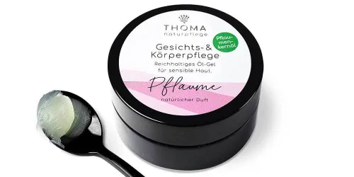 Runde, schwarze Dose mit weiß-rosafarbener Aufschrift Gesichts und Körperpflege Pflaume, reichhaltiges Oel-Gel mit natürlichem Mandelduft für sensible Haut von der Naturseifen Manufaktur Uckermark.