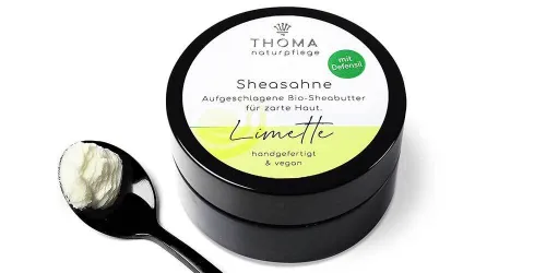 Runde, schwarze Dose mit weiß-gelber Aufschrift Sheasahne Limette, aufgeschlagene Bio-Sheabutter für zarte Haut, handgefertigt und vegan von der Naturseifen Manufaktur Uckermark.