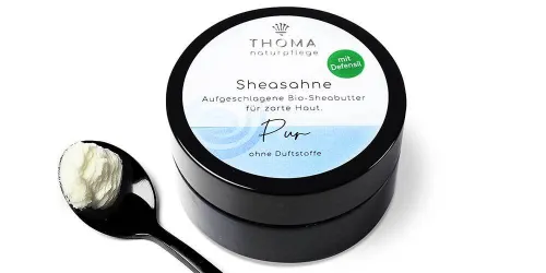 Runde, schwarze Dose mit weiß-blauer Aufschrift Sheasahne Pur, aufgeschlagene Bio-Sheabutter für zarte Haut ohne Duftstoffe von der Naturseifen Manufaktur Uckermark.