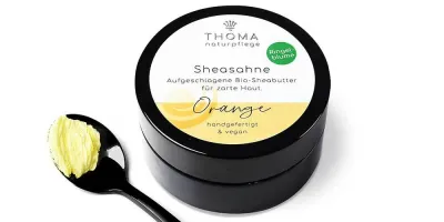 Bio- Ringelblumensalbe mit Sheabutter- vegan Runde, schwarze Dose mit weiß-gelber Aufschrift Sheasahne Orange, aufgeschlagene Bio-Sheabutter mit Ringelblumenoel, handgefertigt und vegan von der Naturseifen Manufaktur Uckermark.