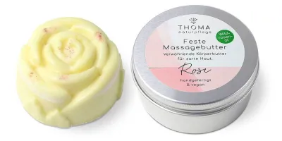 Massagebutter-für alle Sinne Gelbe feste Massagebutter in Rosenform neben silberner Dose mit weiß-rosafarbener Aufschrift Feste Massagebutter Rose, verwöhnende Körperbutter mit Wildrosenoel, handgefertigt und vegan von der Naturseifen Manufaktur Uckermark.