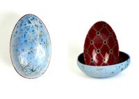Zwei Metalldosen im Fabergé-Stil, eine geschlossen in blau-silbernem Muster, die andere geöffnet mit rotem Innenmuster und goldenen Details, von der Naturseifen Manufaktur Uckermark.