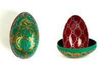 Zwei Metalldosen im Fabergé-Stil, eine geschlossen mit grünem Hintergrund, goldenen Palmen und Ornamenten, die andere geöffnet mit rotem Innenmuster und goldenen Verzierungen, von der Naturseifen Manufaktur Uckermark.